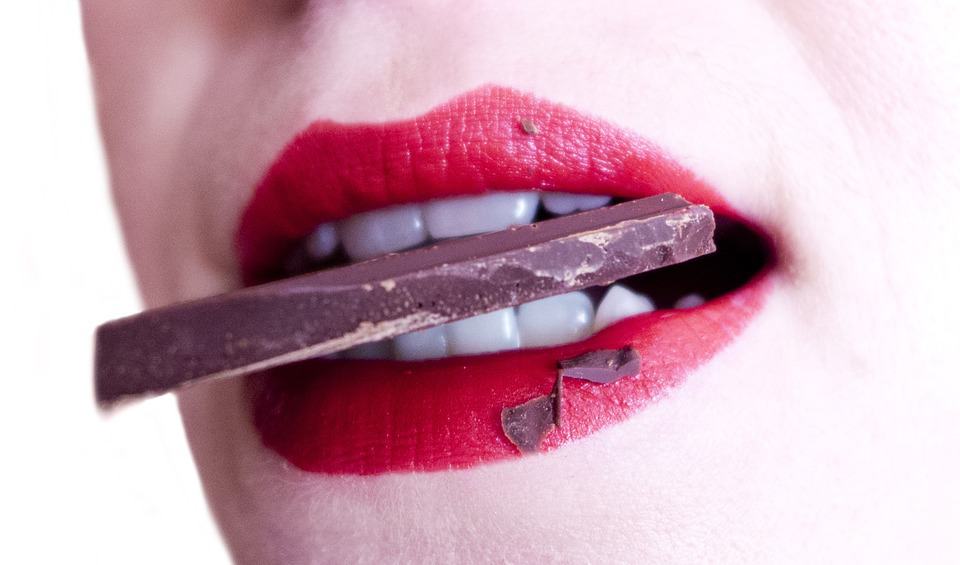 A woman bites into a bar of chocolate that has the potential to stain her teeth.